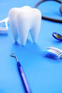 Tooth model on a blue background surrounded by dental tools