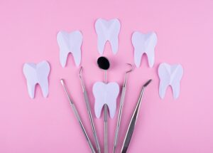 paper teeth and assorted dental tools on a light pink background