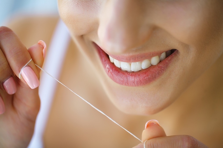 Dental Health. Woman With Beautiful Smile Flossing Healthy Teeth. High Resolution Image