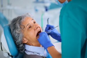 Senior woman during dental procedure at dentist's office.