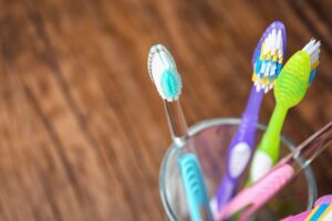 A closeup image of multicolored tooth brushes in a cup.