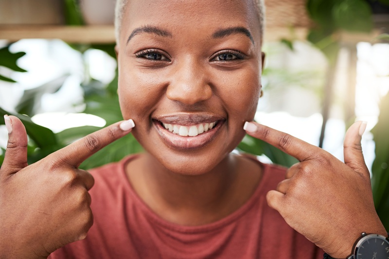 Portrait, smile and black girl is pointing at teeth with happiness for dental hygiene in outdoor. 