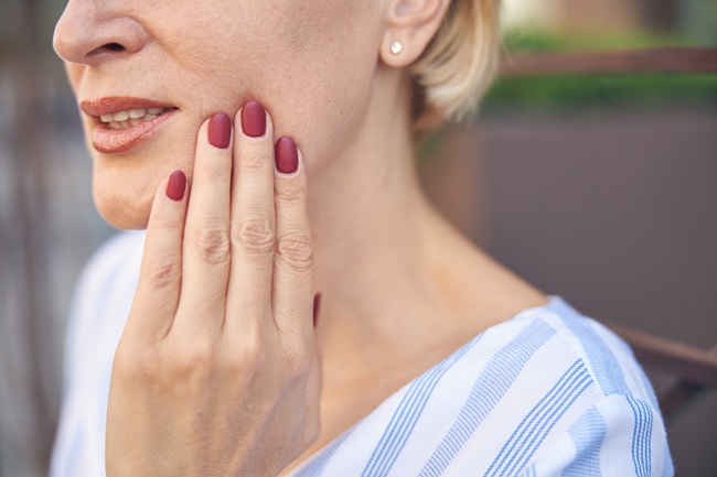 Closeup of a woman touching her face. She has dental pain