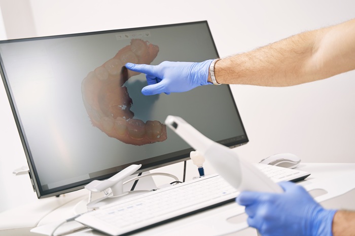 A dentist pointing at a digital rendition of a jaw after using modern dental technology.